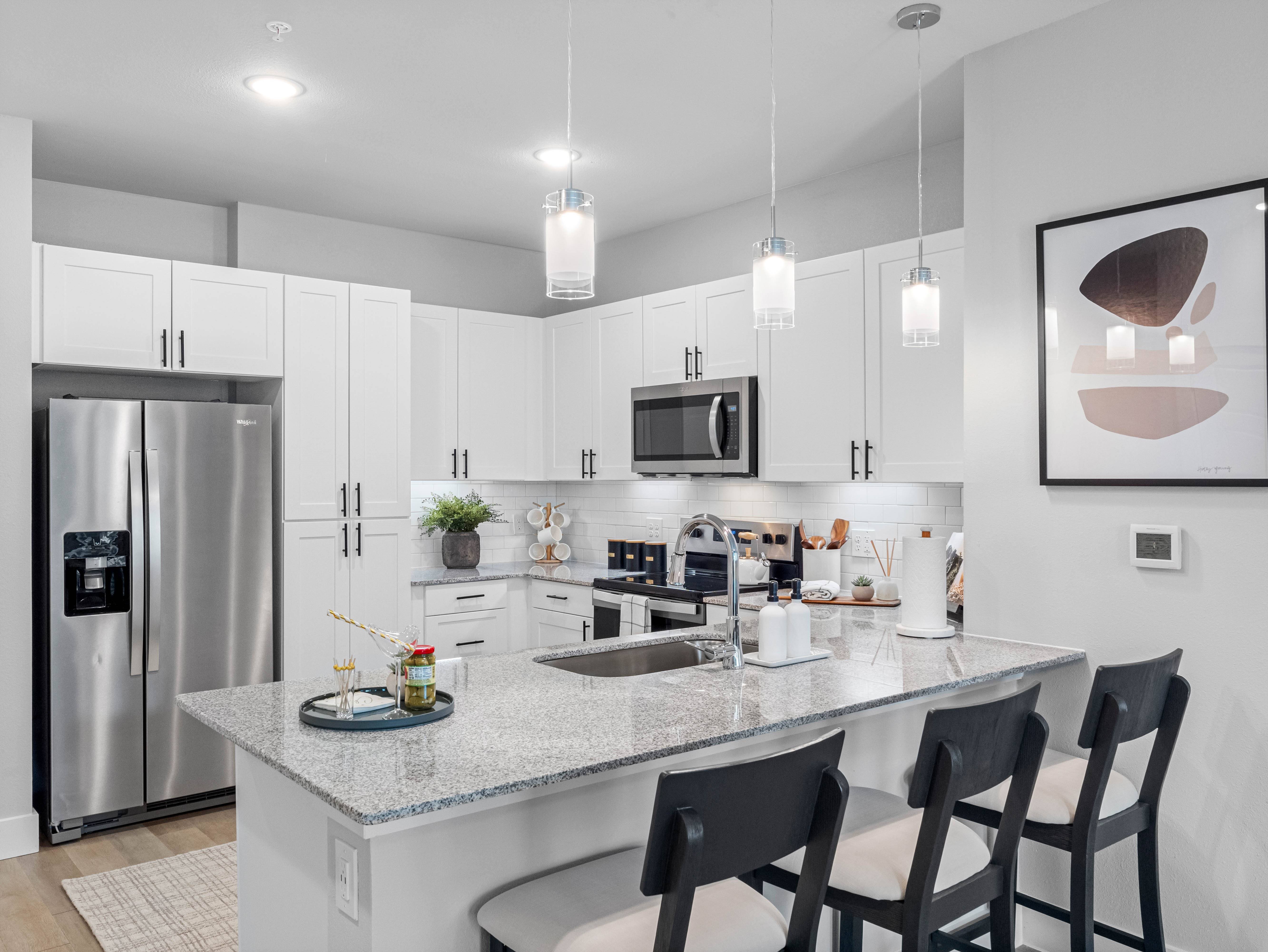 A modern kitchen with a granite countertop and stainless steel appliances.
